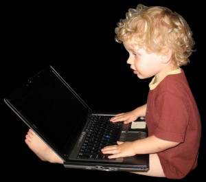 Niño sentando en el suelo con un ordenador en sus piernas